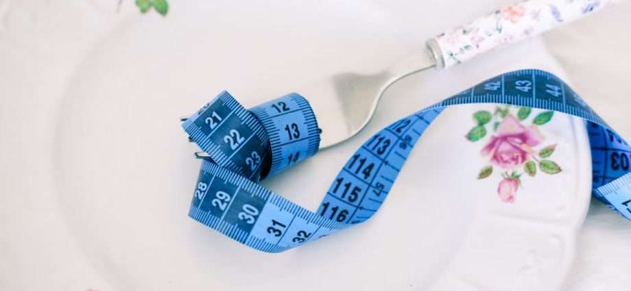 A floral plate with a fork and blue measuring tape symbolizing dieting or healthy eating.