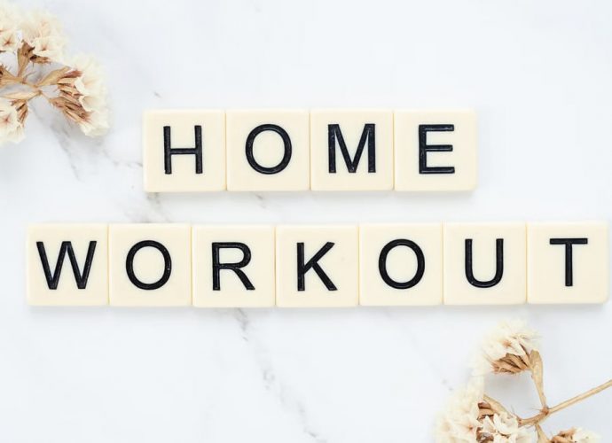 Stylish letter tiles spelling 'Home Workout' on a clean marble background with floral accents.